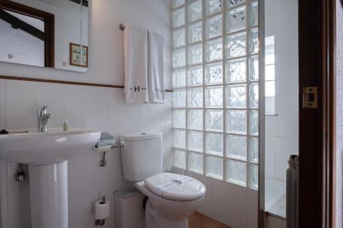 a white bathroom with a toilet and a sink at Apartaments Can Lo in Rupit