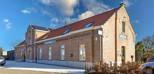 a large brick building with a red roof at Gare 55 in Evergem