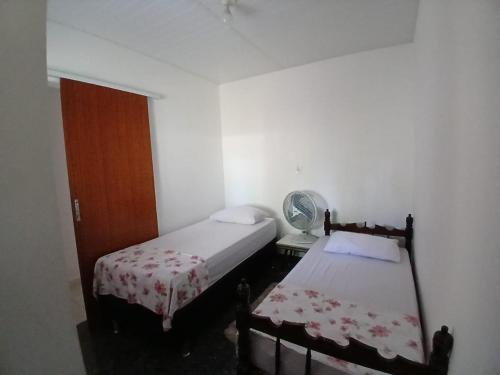 a small bedroom with two beds and a fan at Cantinho da Dê in Anchieta