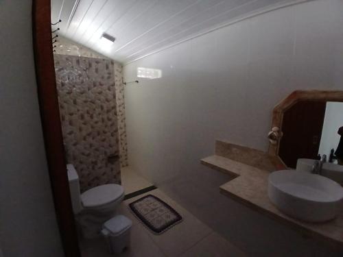a bathroom with a sink and a toilet and a mirror at Cantinho da Dê in Anchieta