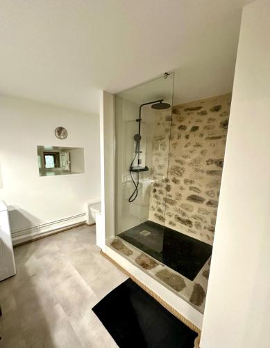a bathroom with a shower with a stone wall at La Pastourelle en Lozère in Le Bacon