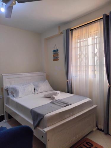 a bedroom with a white bed with a window at Khalisee homes studio apartment 5 in Voi