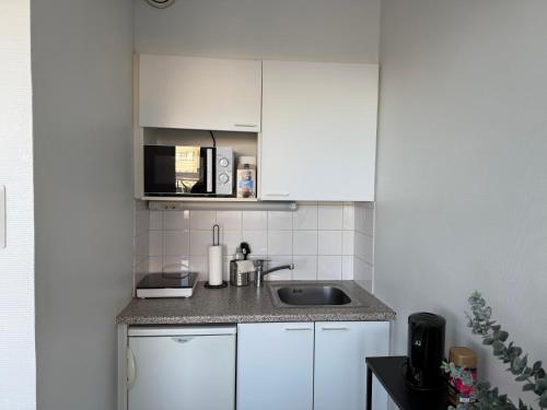 a small kitchen with white cabinets and a sink at Centrum Apartment Kokkola in Kokkola