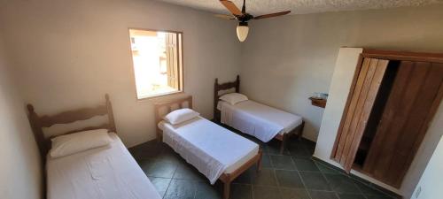 a room with three beds and a window at Bituca Hostel e Café in Milho Verde