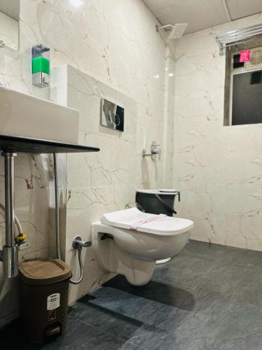 a bathroom with a toilet and a tv on the wall at Imperial Hotel Near Haji Ali in Mumbai