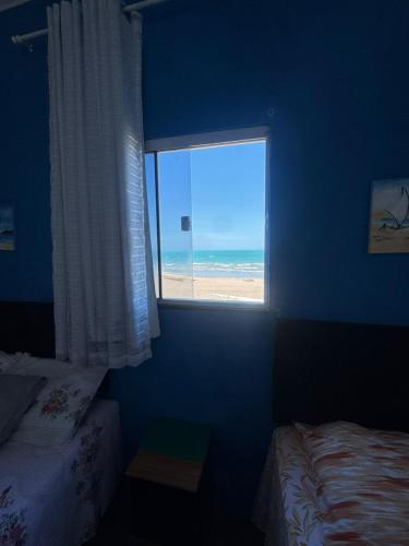 a bedroom with a window with a view of the beach at Chalé marlin azul in Icapuí