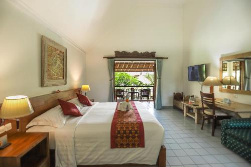 a hotel room with a bed and a table and a desk at Sativa Sanur Cottages in Sanur