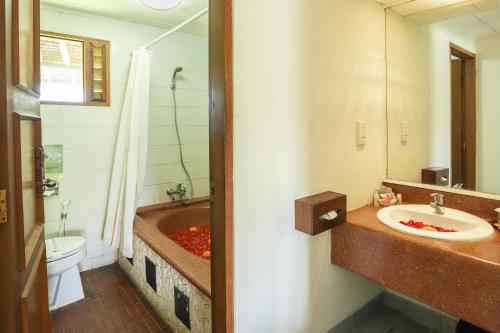 a bathroom with a tub and a sink and a toilet at Sativa Sanur Cottages in Sanur