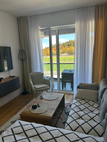 a living room with a couch and a chair and a piano at Apartman MAD Bjelasnica in Bjelašnica