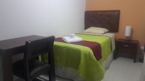a bedroom with a bed with a table and a chair at Hotel Portal Colonial in San José