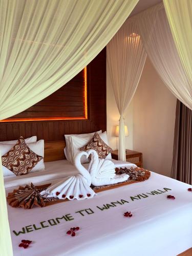 a bedroom with two white beds with red flowers on them at Wana Ayu Jelijih Villas by Dhananjaya Hospitality in Tampaksiring