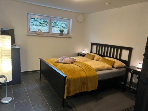 a bedroom with a bed with a yellow blanket and two windows at Ferienwohnung im Hasenwieschen in Kaisersesch