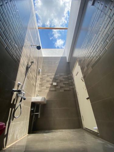 a bathroom with a shower and a sink and a window at Wooden Villa in Kanchipuram