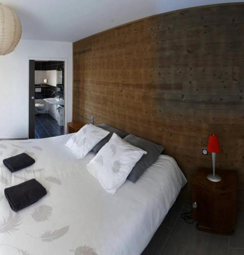 a bedroom with a white bed with a wooden wall at Lapin in Lesquin
