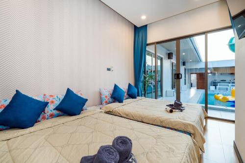 two beds in a bedroom with blue pillows at You Baan Pool Villa Cha-am in Ban Bo Prakhon