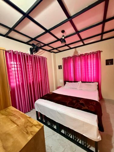 a bedroom with pink curtains and a large bed at Skylark Home in Mananthavady