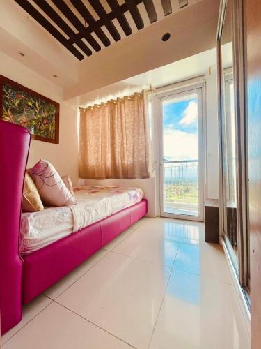 a bedroom with a pink couch and a large window at The Wind Escape Netflix-Ready Staycation for 4 in Tagaytay