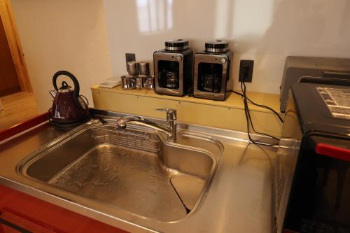 a kitchen sink with two coffee makers on a counter at Kamakura in Iiyama