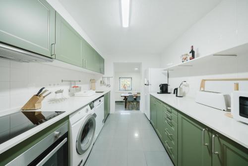 a kitchen with green cabinets and a washer and dryer at Quinta biológica, com vista, na Serra de Sintra in Sintra