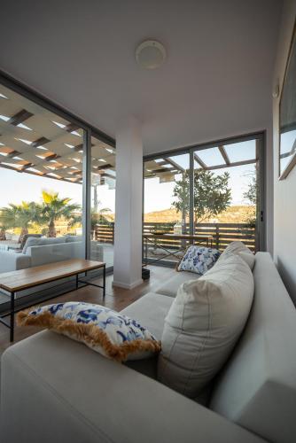 a living room with a couch and tables and windows at Villa Tata - Private Pool, Garden & Mountain View near the Sea in Metókhi