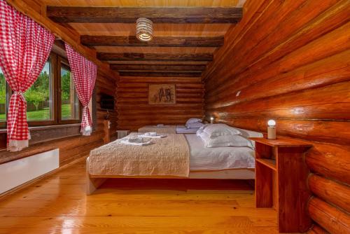 a bedroom with a bed in a log cabin at Log Cabin Valley - Private Villa with Pool in Gospić