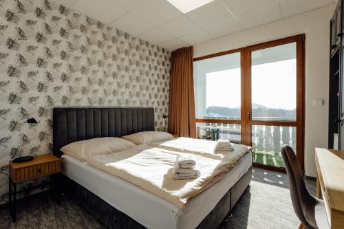a bedroom with a bed and a table and a window at Penzión Topky in Banská Štiavnica