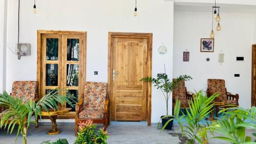 a room with two doors and chairs and plants at Breezy Resort in Arugam Bay
