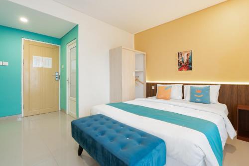 a bedroom with a large bed with a blue bench at Sans Hotel Elrose Place in Samarinda