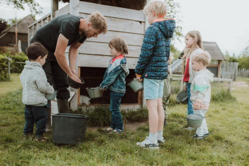 a group of children standing around a man with buckets at Landhoeve in Oosterwolde