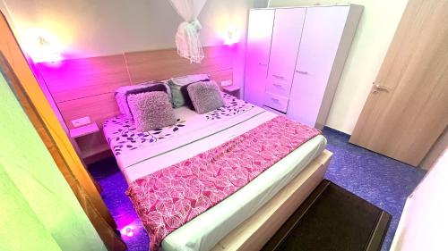 sypialnia z różowym łóżkiem, fioletowymi prześcieradłami i poduszkami w obiekcie Dream Home Design w mieście Mbalngong