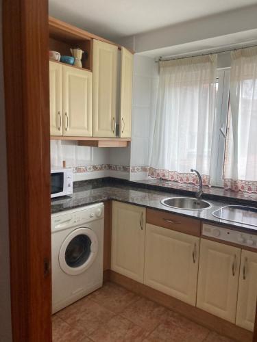 a kitchen with a sink and a washing machine at Liencres Apartment in Liencres