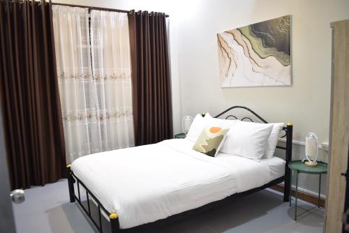 a bedroom with a bed and a window at Khwanlom House in Lampang