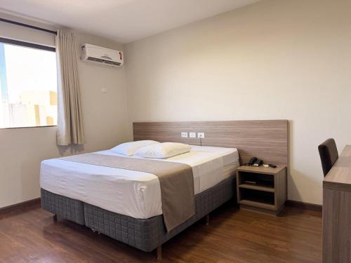 a bedroom with a large bed and a window at Arca's Hotel Umuarama in Umuarama