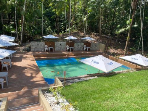 a pool with umbrellas and tables and chairs at Eco Hotel Mãe De Sagui in Castanhal