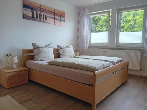 a bed in a bedroom with two windows at Gästehaus Dietrich in Bad Sooden-Allendorf