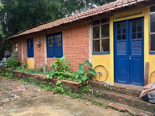 a small brick house with blue doors and windows at Casinha Rústica de Paty in Paty do Alferes