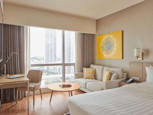 a hotel room with a bed and a couch at Novotel Executive Hotel at Rosalina Acqua Residence Mandaluyong in Manila