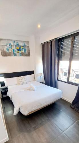 a bedroom with a large white bed and windows at AYZ Ulises - Auto check-in property in Madrid