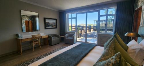 a bedroom with a bed and a desk and a large window at Big Sky Ranch in Colesberg