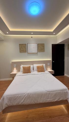 a bedroom with a large white bed with a blue light at One Bedroom with Balcony in Abreeza Mall in Davao City
