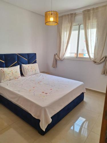 a bedroom with a bed with a blue headboard and a window at Super Logement in Tangier
