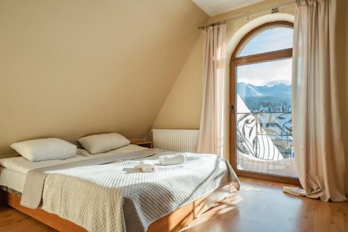 a bedroom with a bed and a large window at Willa TOSKA in Murzasichle