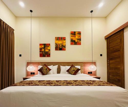 a bedroom with a large bed and some paintings on the wall at Golden Villa Lovina in Lovina