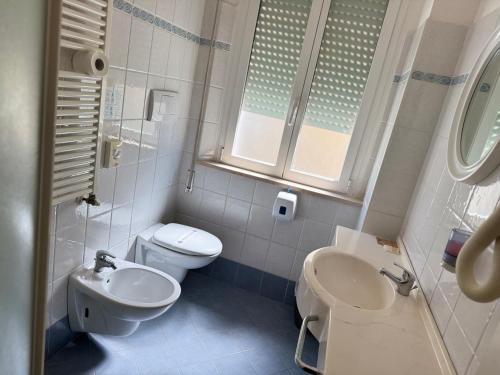a white bathroom with a toilet and a sink at Hotel Alcazar in Rimini