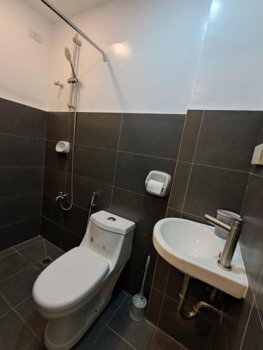 a bathroom with a toilet and a sink at Urdaneta City Modern Condo in Bayaoas