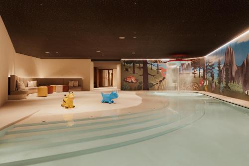 ein Schwimmbad mit zwei Winnie-Puuh-Figuren in einem Zimmer in der Unterkunft The Oswald Grand Hotel in Wolkenstein in Gröden