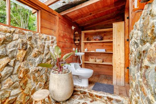 a bathroom with a toilet in a stone wall at Refugio para desconectar, cabaña del ermitaño en medio del bosque in La Ceja
