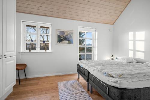 a bedroom with a bed and two windows at Feriehus 1150 in Ringkøbing