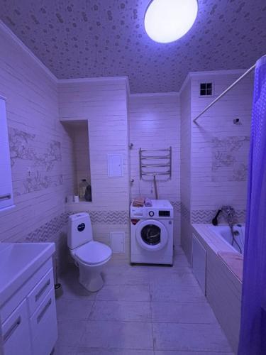 a white bathroom with a toilet and a washing machine at высотка 15 in Aktobe
