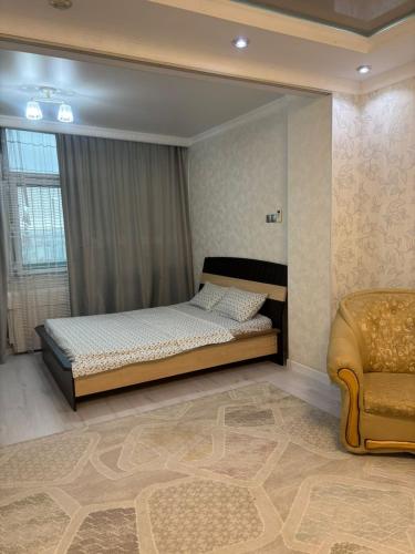 a bedroom with a bed and a chair at высотка 15 in Aktobe